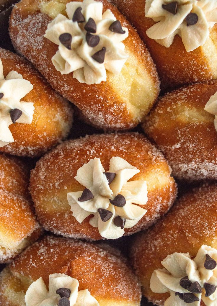 a pile of doughnuts with white frosting and chocolate chips