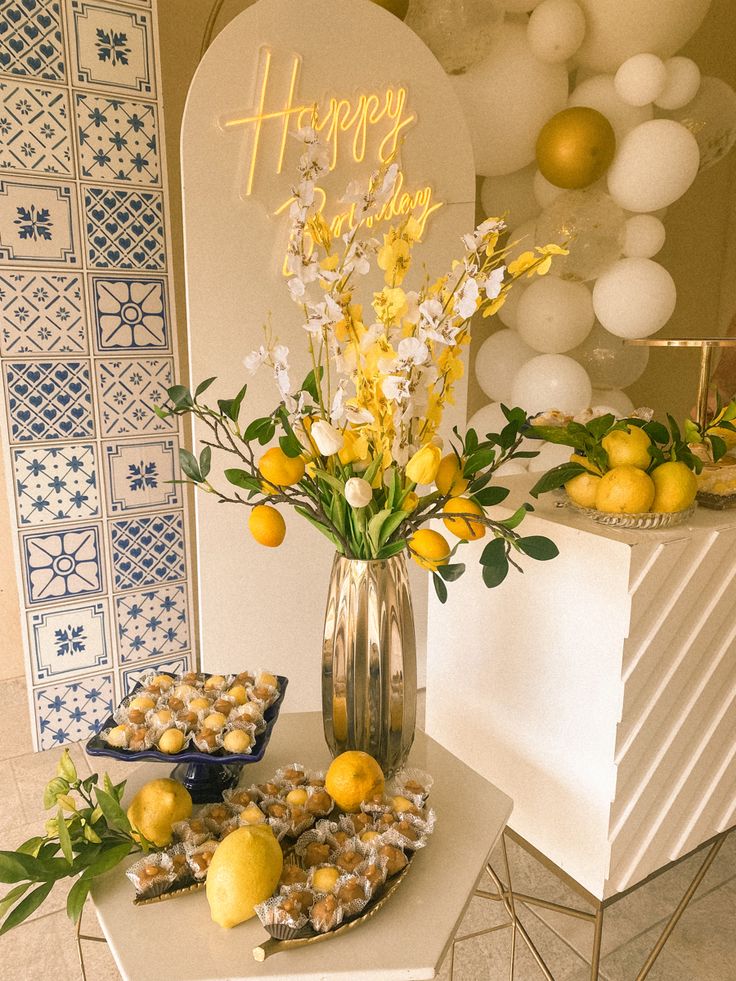 a table topped with lemons and pastries next to a vase filled with flowers