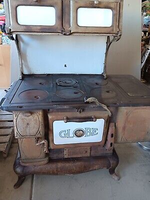 an old fashioned stove with two burners on it in a room filled with other items