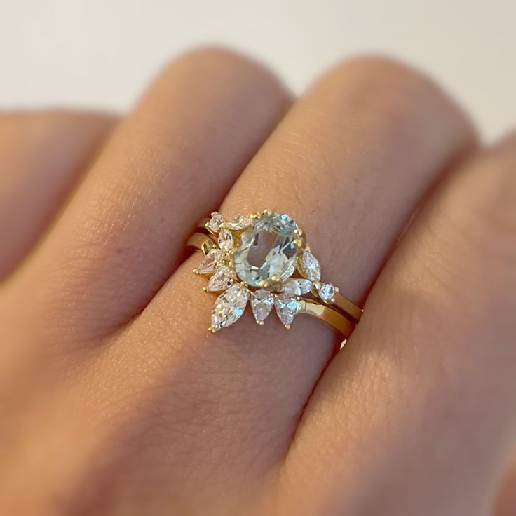 a woman's hand holding a ring with an oval shaped diamond and two smaller round diamonds