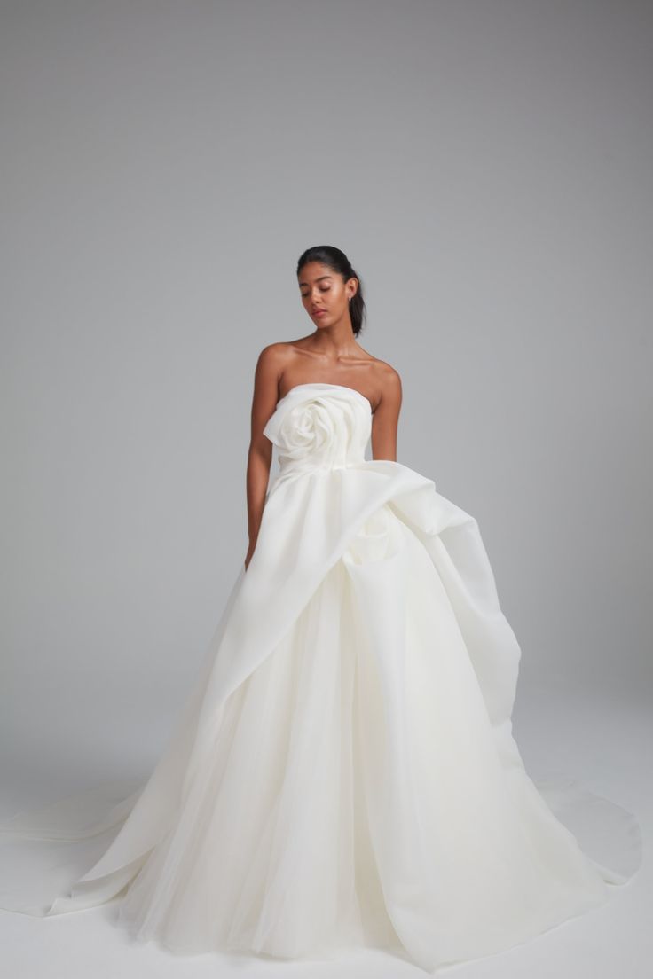 a woman in a white wedding dress standing on a gray background