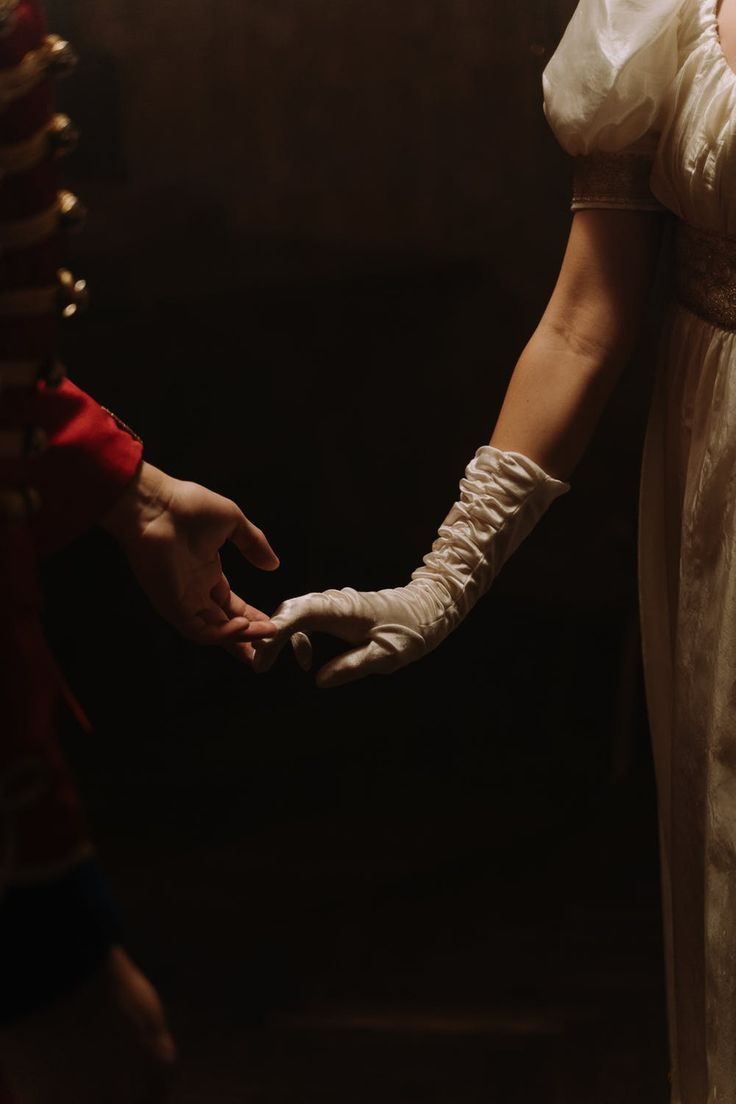 two people dressed in period clothing holding hands