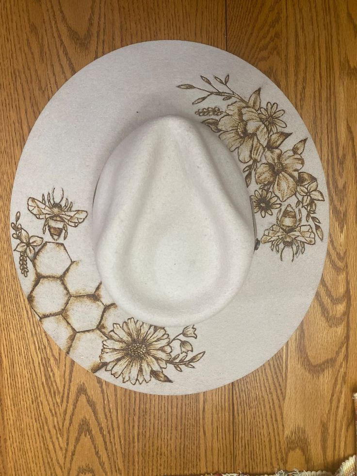 a white hat with flowers and bees on it