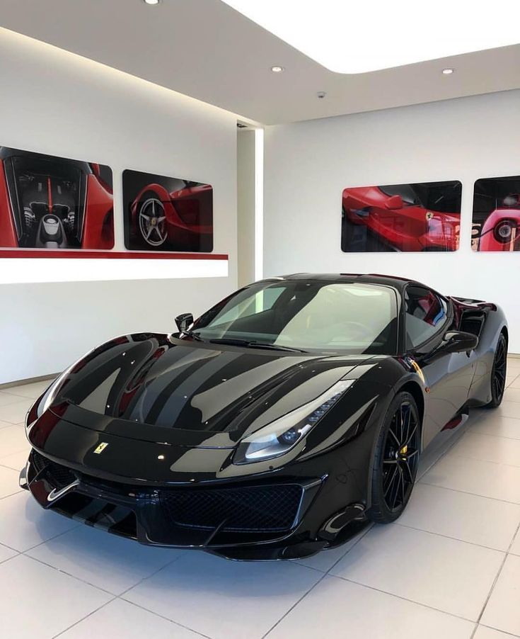 a black sports car in a showroom with pictures on the wall and flooring