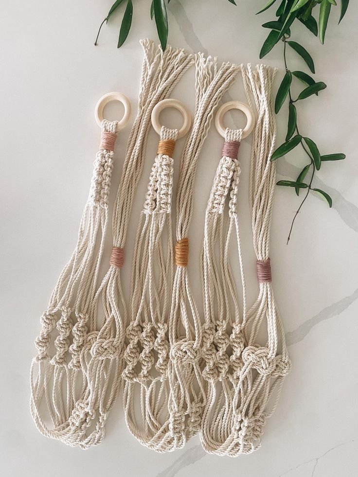 four macrame keychains with wooden handles and ropes attached to each other