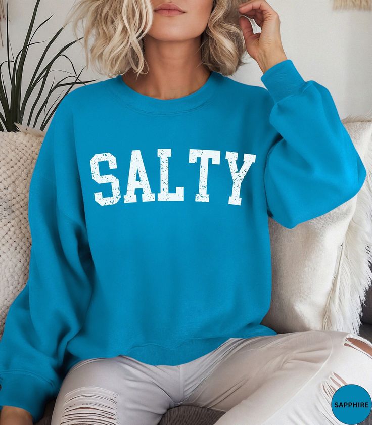 🏝️Discover our Salty Beach Vibes Summer Beach Vacation crewneck Sweatshirt!🏝️ This Trendy beachy sweater features an eye-catching white distressed graphic design. It is super soft and comfortable and designed to enhance your beach vibes. It will have you dreaming of your next beach vacation! Perfect as an oversized beach cover up or wear it with jeans or shorts for a super cute look on a casual day out. Makes a nice gift for a Birthday or for a Beach lover! Comes in 14 pretty colors. ✨PRINT: This is a handmade, Direct-to-Garment printed item. The designs are professionally printed directly on to the shirt. All over printing is used. The ink is printed directly into the fabric. ✦Images may sometimes appear larger in the photo than in person due to images being a close up on the screen so Blue Crew Neck Sweatshirt For Beach Season, Beach Season Long Sleeve Letter Print Sweatshirt, Blue Cotton Beach Sweatshirt, Blue Cotton Sweatshirt For Beach, Blue Relaxed Fit Sweatshirt For Beach Season, Casual Sweatshirt For Beach Season, Casual Sweatshirt For Beach Season Leisure, Blue Crew Neck Sweatshirt For Vacation, Trendy Crew Neck Sweatshirt For Beach