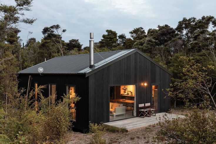 a small black cabin in the woods at night