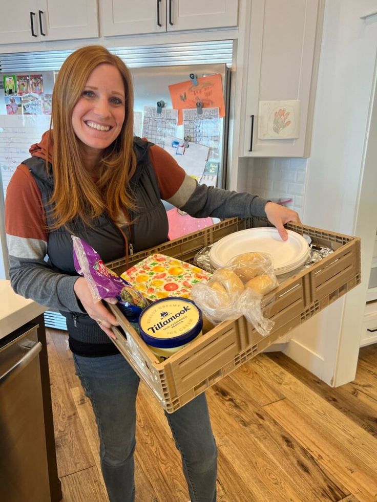 a woman holding a basket full of food in her hands and smiling at the camera