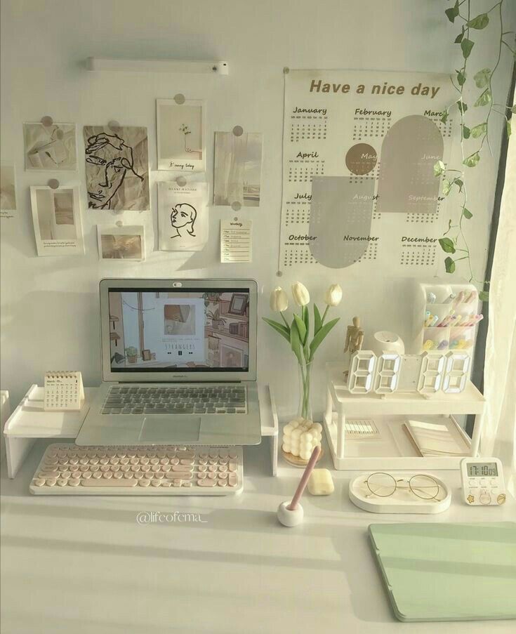 a laptop computer sitting on top of a desk next to a vase with flowers in it