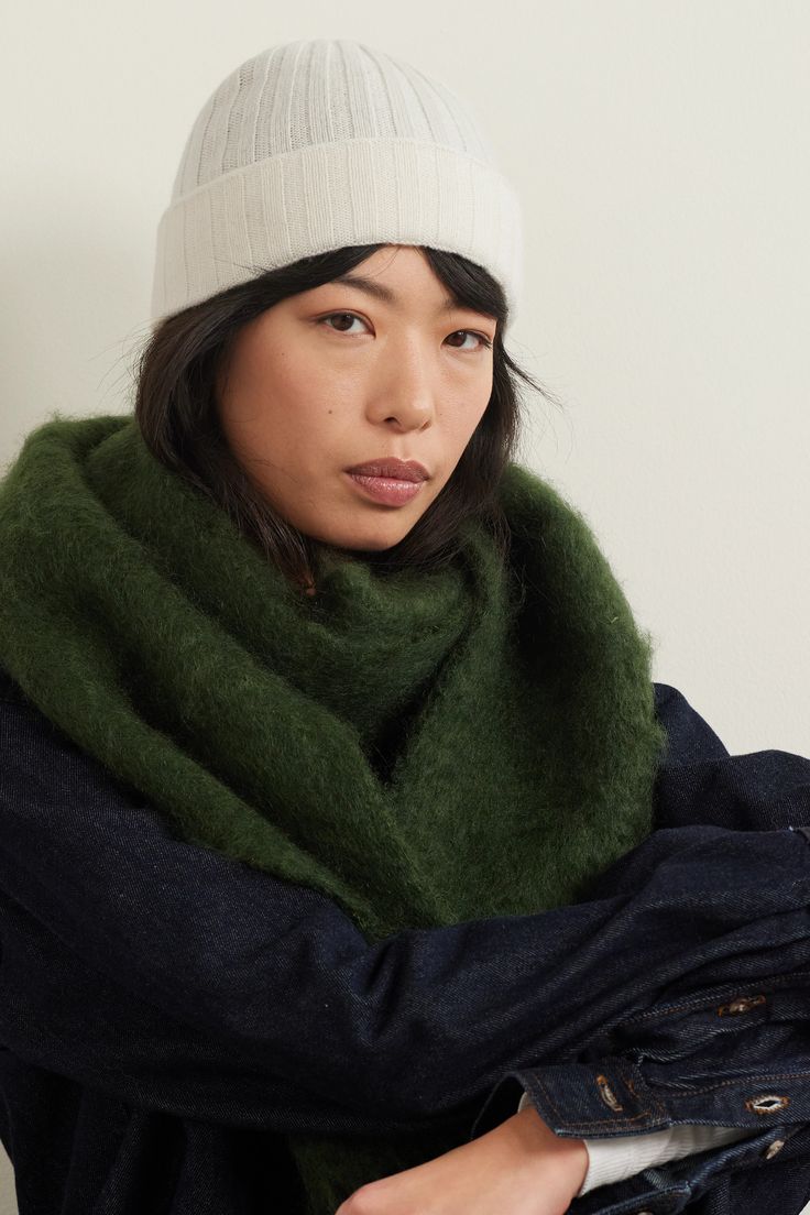 a woman wearing a white hat and green scarf