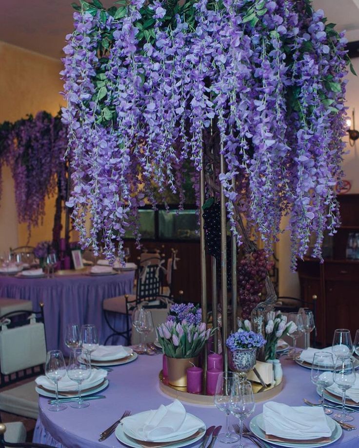 the table is set with purple flowers and place settings