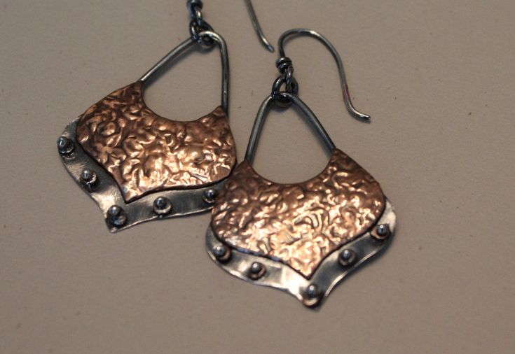 "Textured copper shapes are affixed to sterling silver and adorned with silver beads to add dimension and interest. The pair are highly oxidized for a rustic finish. Lots of movement and sway. Very easy to wear, quick on/off with the silver ear wires, and lightweight. These earring hang just over 2\" from your piercing and are an inch at their widest. Visit my shop: https://www.etsy.com/shop/MyFascinationStreet Connect with me on... www.FascinationStreetDesigns.com Facebook: https://www.facebook Mixed Metal Earrings, London Blue Topaz Ring, Silver Spinner Rings, Earrings Bohemian, Silver Jewelry Handmade, Bohemian Earrings, Tampa Fl, Metal Work, Metal Earrings