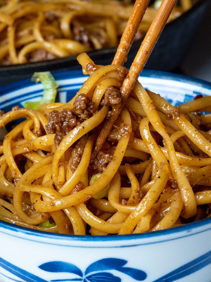 noodles with meat and chopsticks in a blue and white bowl