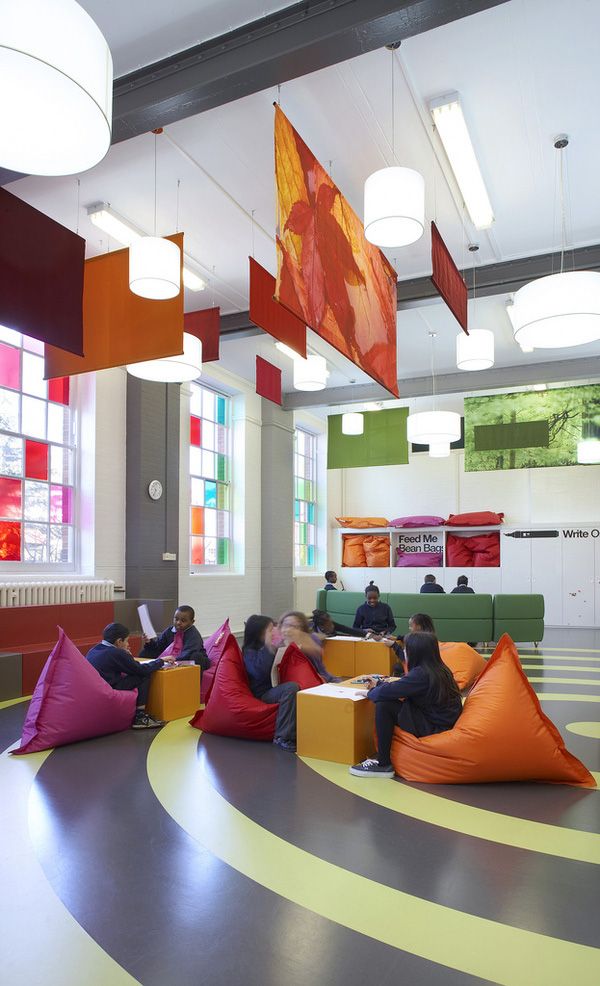 people sitting on bean bag chairs in a large room with colorful walls and flooring