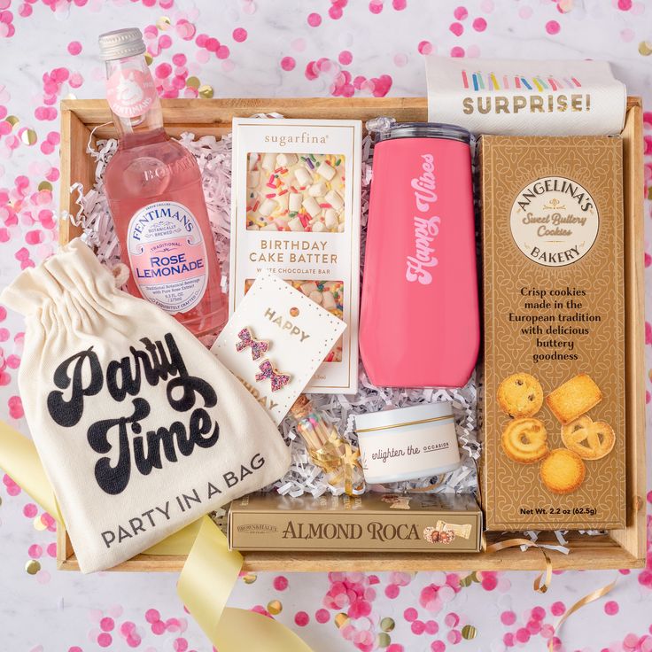 an open box with various items in it on a pink and white tableclothed surface