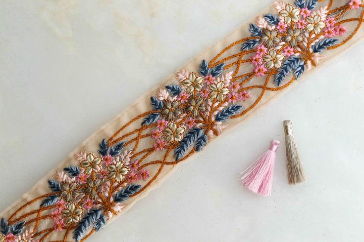 an embroidered ribbon with flowers and tassels on it