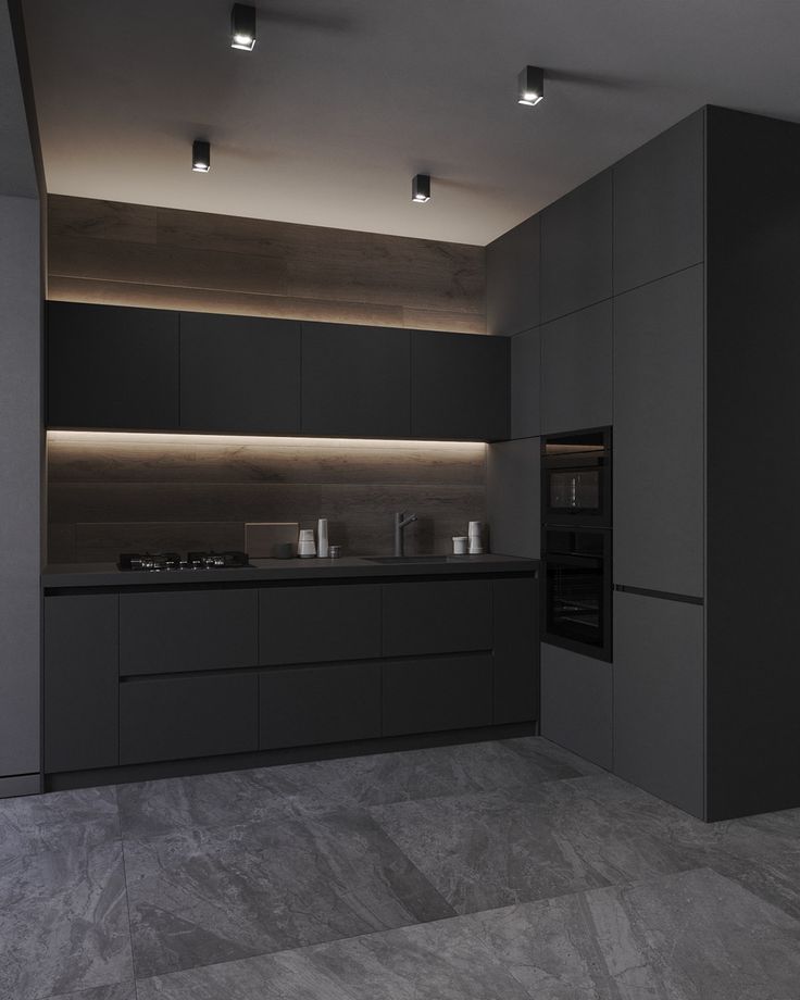 an empty kitchen with black cabinets and counter tops, lights on the ceiling above it