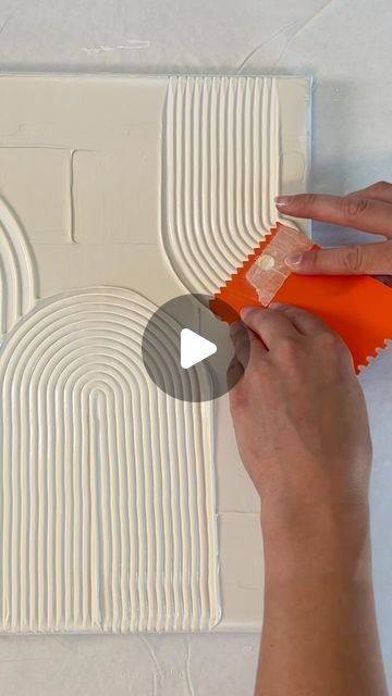 a person is painting a wall with white paint and orange paper strips on it,