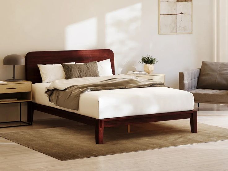 a bed sitting on top of a wooden floor next to a chair and table in a room