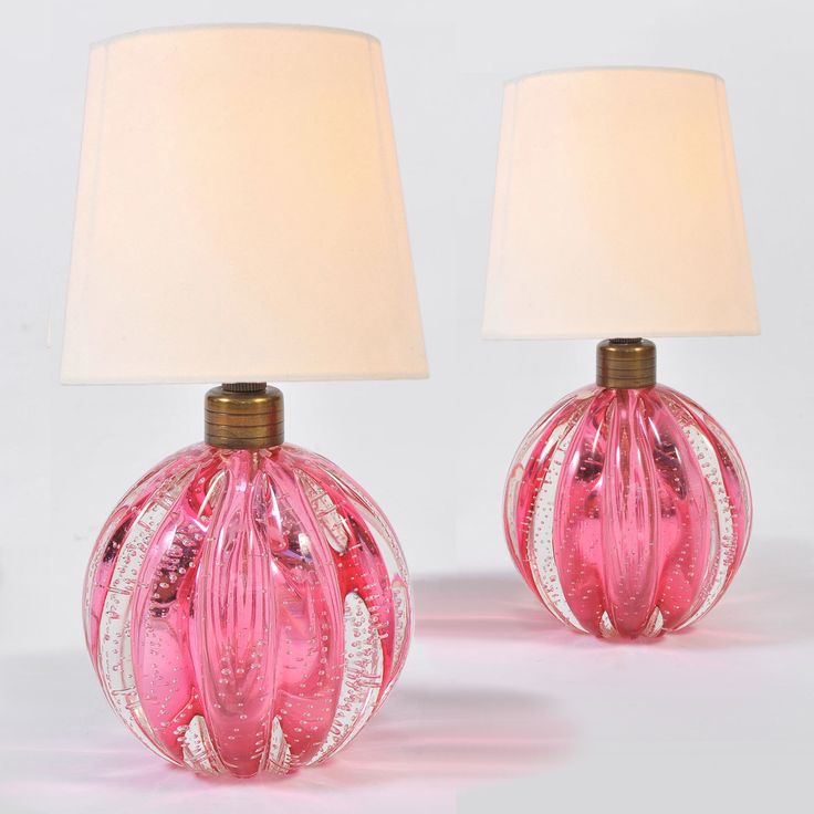 two pink glass lamps sitting next to each other