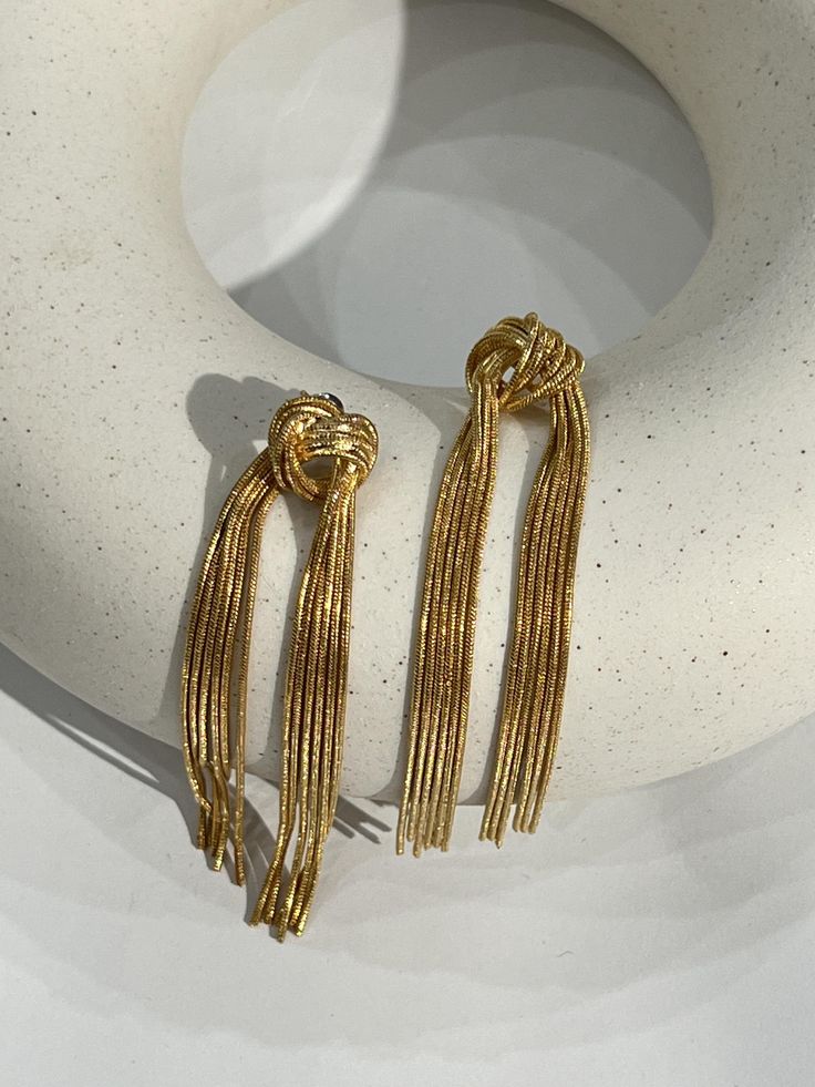 These Gold Tied Tassel Earrings are the perfect accessory to turn heads everywhere you go. With a sophisticated appeal, these earrings feature tied tassels in a gold plating. The ultimate combination of elegance and glamour, these earrings will make a statement. Elegant Yellow Gold Earrings With Tassels, Gold Tassel Drop Earrings For Formal Occasions, Gold Tassel Earrings With Fringe For Evening, Gold Tassel Earrings For Formal Occasions, Gold Elegant Tassel Earrings For Party, Gold Tassel Dangle Earrings For Formal Occasions, Gold Dangle Tassel Earrings For Formal Occasions, Gold Tassel Earrings For Party, Formal Gold Dangle Tassel Earrings