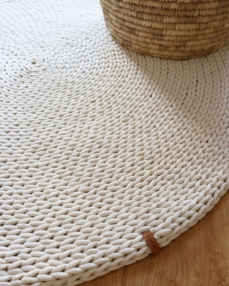 a basket sitting on top of a wooden floor next to a white rug and a woven mat