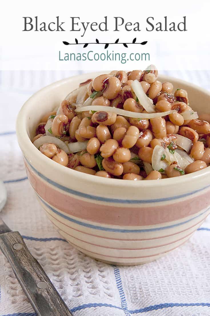 a bowl filled with beans and onions on top of a table next to a fork