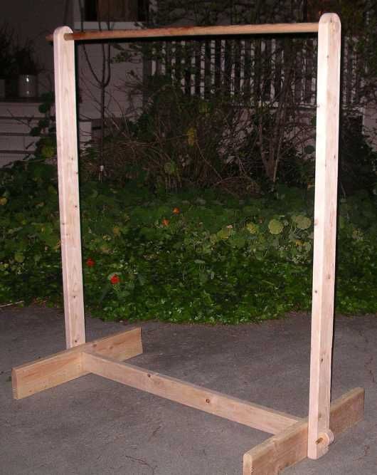 a wooden frame sitting on top of cement next to bushes and flowers in the background