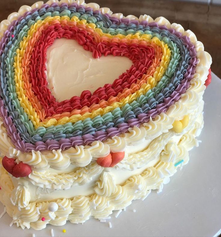 a cake with white frosting and multicolored icing in the shape of a heart