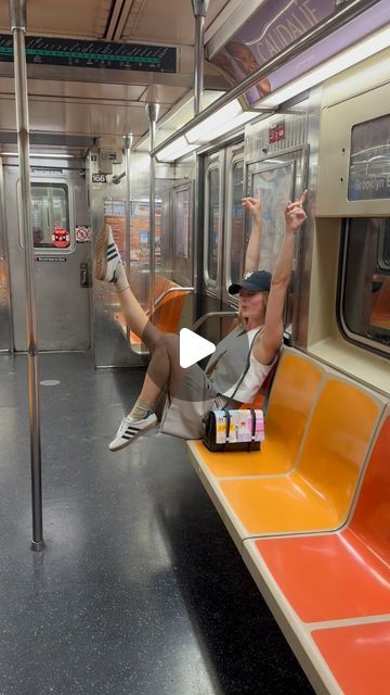 a man sitting on a subway train with his arms in the air and legs up