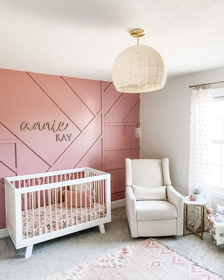 a baby's room with pink walls and white furniture