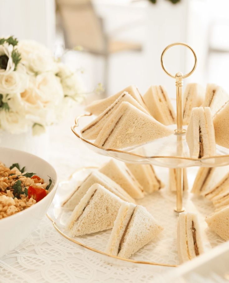 there are sandwiches and rice on the tray next to a bowl of salad, with flowers in the background