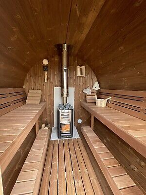 the inside of a wooden sauna with benches and a wood stove in the center