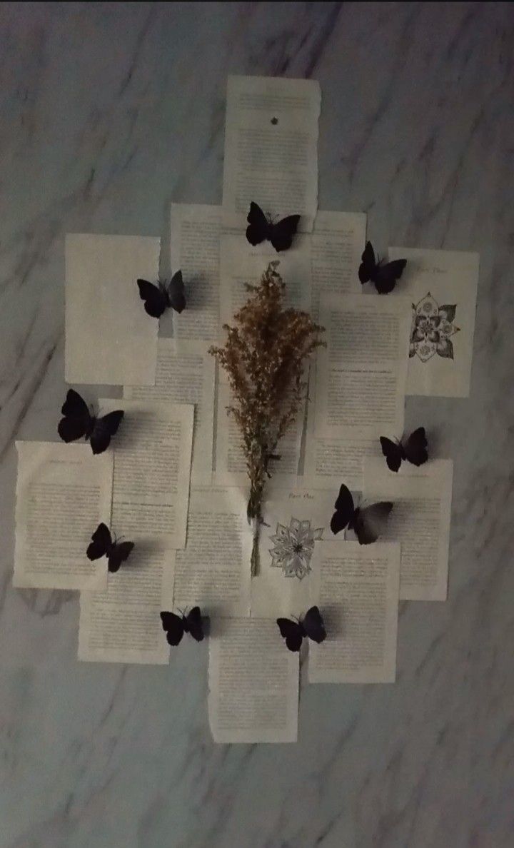 an arrangement of butterflies and books on a marble table with white paper in the middle