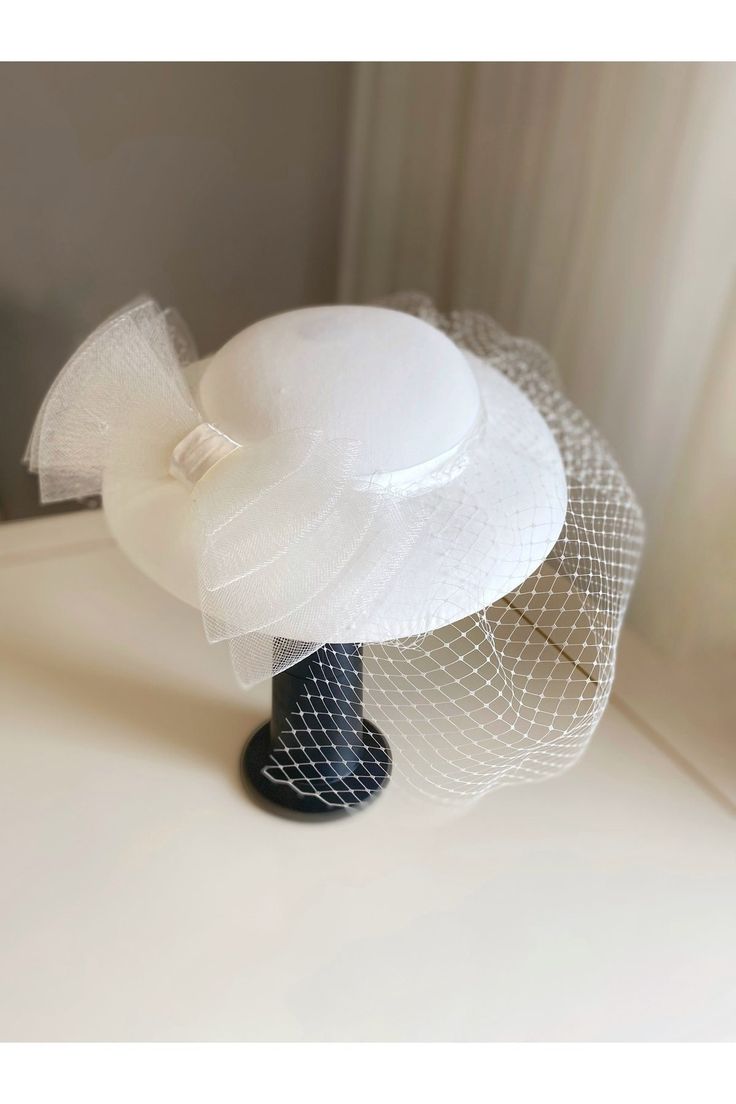 Bridal Hats, Pillbox Hats, and Fascinators - Elegance in Every Detail! *This product is handmade and special design. Made of fabric, the inner material is also a type of fabric, means that there is no filling! The bowknot is made of tulle. *The color is off-white, compatible with general wedding dress colors. *It is made in a standard one-size which is 30 cm, suitable for most women to wear. *It has elastics that can be clipped to the hair, or pinned to the scarf. *Not washable! it can be carefu Gatsby Style Wedding Fascinator With Short Brim, White Brimmed Felt Hat For Party, White Curved Brim Felt Hat For Parties, Adjustable Top Hat With Structured Crown For Church, White Felt Hat With Curved Brim For Party, White Adjustable Hat With Structured Crown, White Adjustable Hats With Structured Crown, Elegant White Fitted Bonnet, Elegant Spring Bonnet