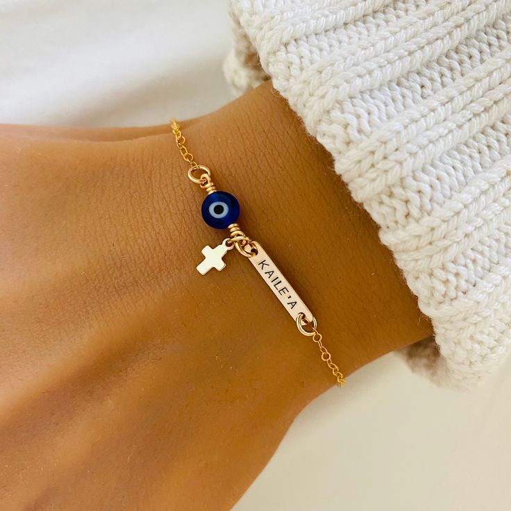 Dainty Evil Eye Bracelet, Baby First Bracelet, Christening Jewelry, Cross Bracelet, Protection Jewelry, Amulet Bracelet, Blue Evil Eye ❤ Available in silver, gold and rose gold. ❤ Specification . All components are 925 Sterling Silver/ 14K Gold Filled/ 14K Rose Gold Filled . Evil Eye bead size is 6mm . Bar size is 16 x 3.2mm . Length includes pearl, jump ring and clasp . Comes in our signature pouch ready for gift giving ❤ Religious Bracelets: http://etsy.me/2s2rTLz ❤ Religious Necklaces: http://etsy.me/2rITweG ❤ All collections from StampedEve: https://www.etsy.com/au/shop/StampedEve?ref=l2-shopheader-name IMPORTANT: Usually jewellery in the pictures looks bigger than in reality. Please consider all given dimension and compare them to the ruler before ordering. ❤ About My Jewellery Each p Personalized Blue Bracelets, Blue Personalized Spiritual Bracelets, Personalized Blue Spiritual Bracelets, Spiritual Personalized Blue Bracelets, Blue Name Bracelet For Mother's Day Gift, Mother's Day Blue Name Bracelet Gift, Blue Friendship Bracelets With Charms, Blue Rosary Bracelet Gift, Religious Necklaces