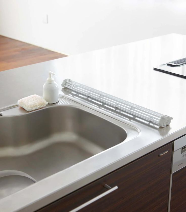 a stainless steel kitchen sink with cleaning products on the counter top next to an appliance