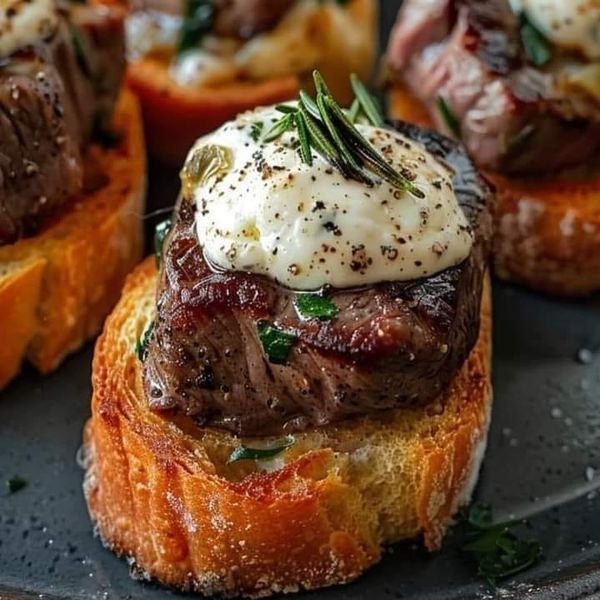 steak sandwich with sour cream and herbs on top, served on toasted buns