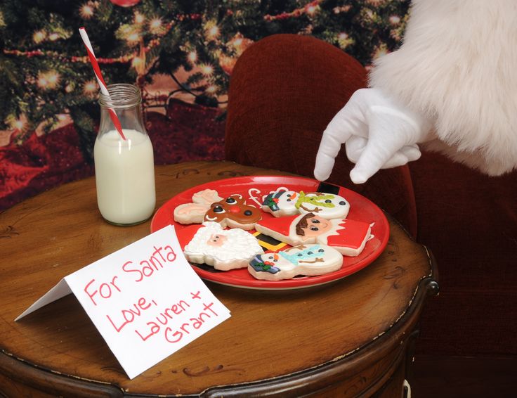 a red plate topped with lots of cookies next to a glass of milk and santa clause