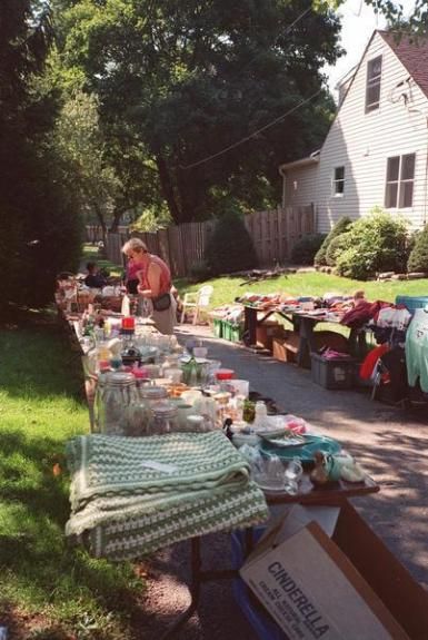 an outdoor flea market is set up on the side of the road in front of a house