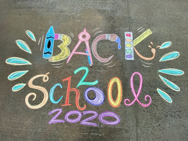 back to school written in chalk on the sidewalk with crayons and pencils