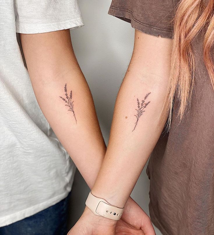 two people holding hands with small tattoos on their arms, one has a flower in the other's left arm