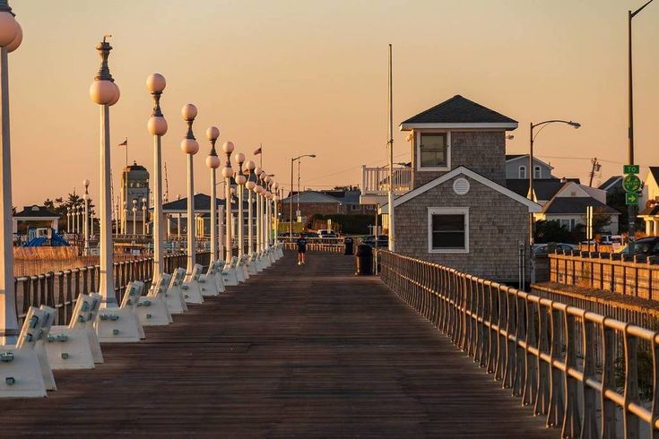 a wooden bridge with many lights on each side and a small building in the background