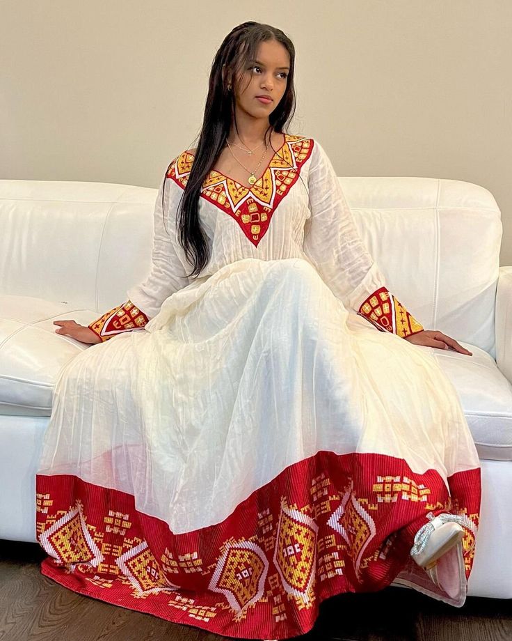 This Habesha Kemis, a traditional Ethiopian garment, radiates beauty and elegance, reflecting the rich cultural heritage and craftsmanship of Ethiopia. This exquisite dress showcases a perfect harmony of handwoven fabric, intricate embroidery, the use of Menen fabric, lightweight cotton, and quality thread, creating a stunning ensemble that captivates the eye and the heart. At the core of the Habesha Kemis lies the handwoven fabric, a testament to the skill and dedication of Ethiopian weavers. U Habesha Traditional Dresses, Ethiopia Clothing, Ethiopian Dresses, Eritrean Clothing, Eritrean Dress, Mother Africa, Ethiopian Clothing, Habesha Dress, Ethiopian Traditional Dress