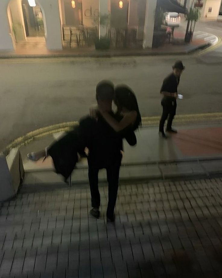 two people hugging each other on the sidewalk