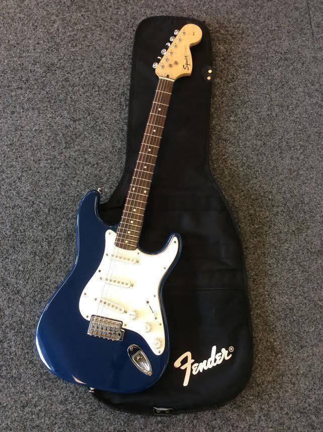 a blue and white guitar sitting on top of a black hard shell case with the fender logo on it