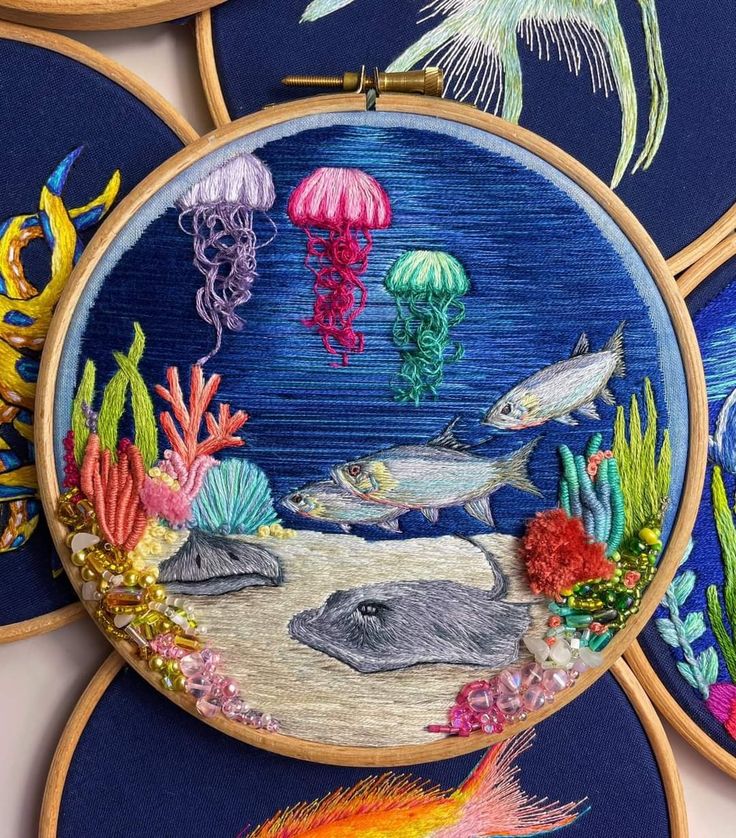 some embroiderys are hanging on the wall with sea animals and jellyfish in them