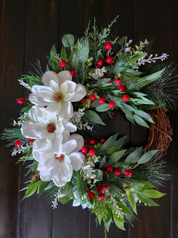 a christmas wreath with white flowers and greenery