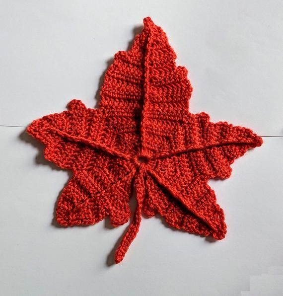 a red knitted leaf laying on top of a white surface