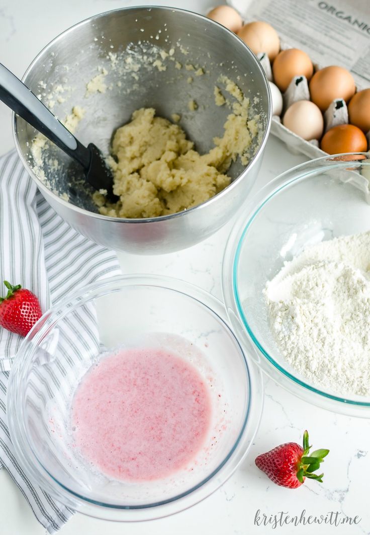 ingredients to make strawberry shortcakes are shown in bowls on a counter top with eggs, flour and strawberries